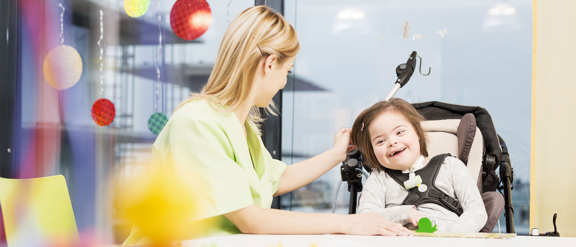 Pflegekraft und lachendes Mädchen im Rollstuhl